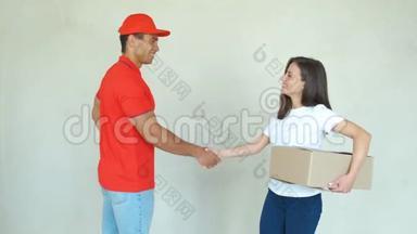 送货<strong>服务人员</strong>穿制服送包裹给妇女。 男人拿着盒子，微笑着握手